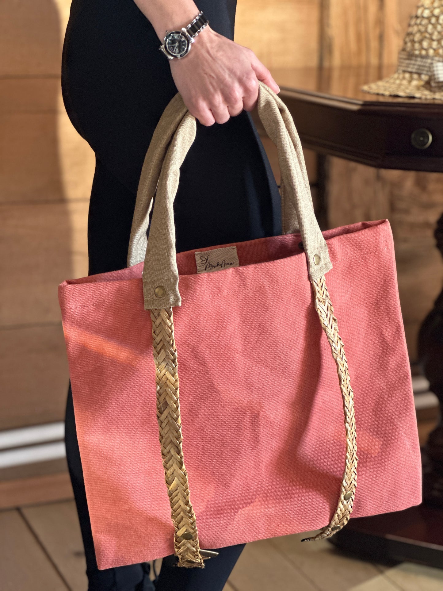 Peach tote bag with straw handles for carrying a hat