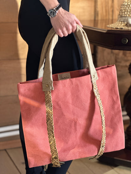 Peach tote bag with straw handles for carrying a hat