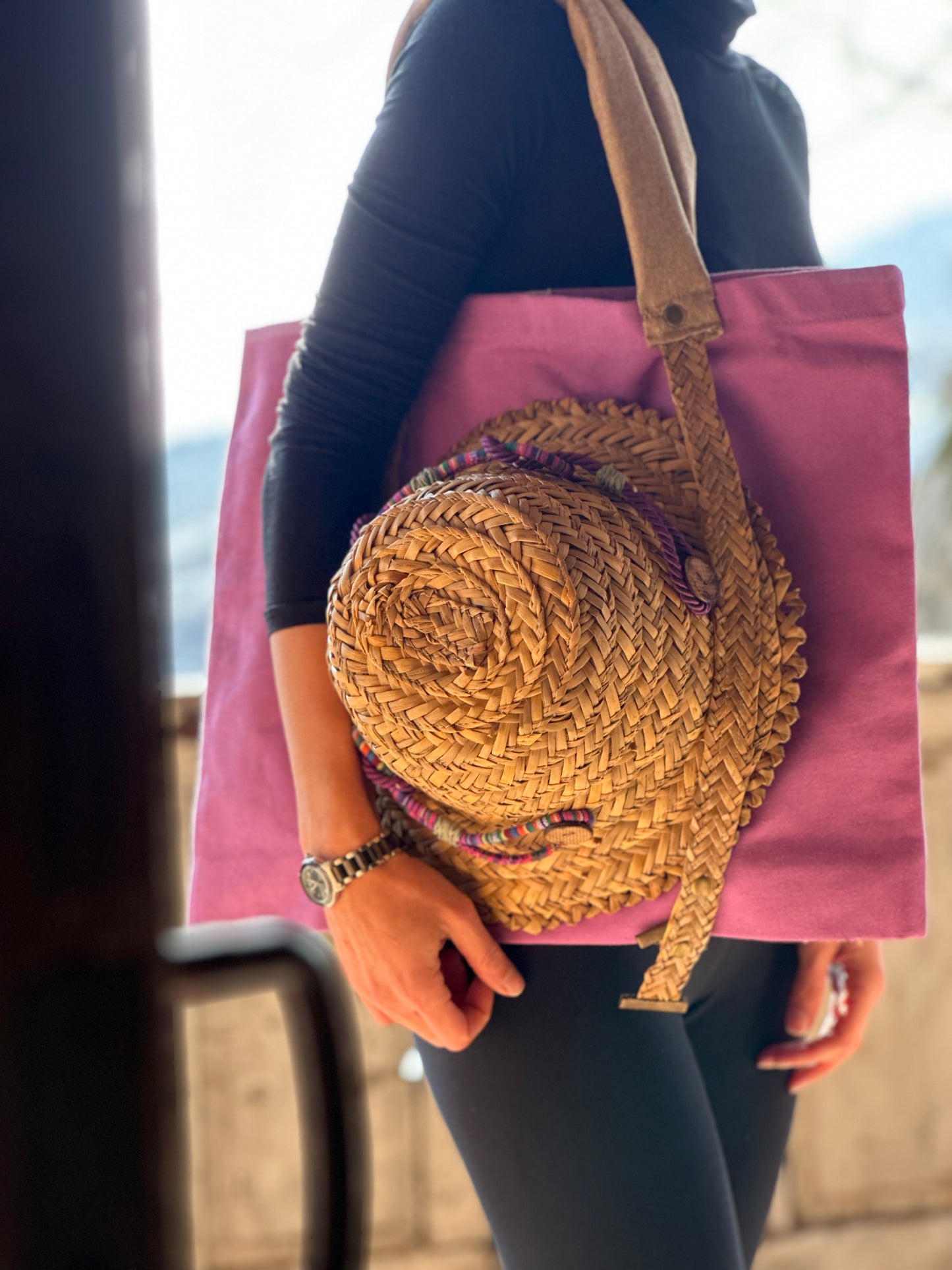 Purple tote bag with straw handles for carrying a hat
