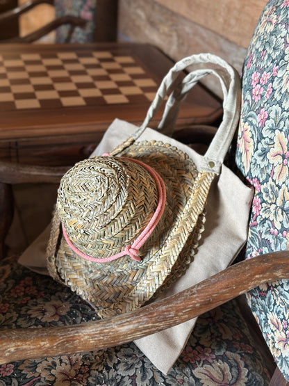 Beige tote bag with straw handles for carrying a hat