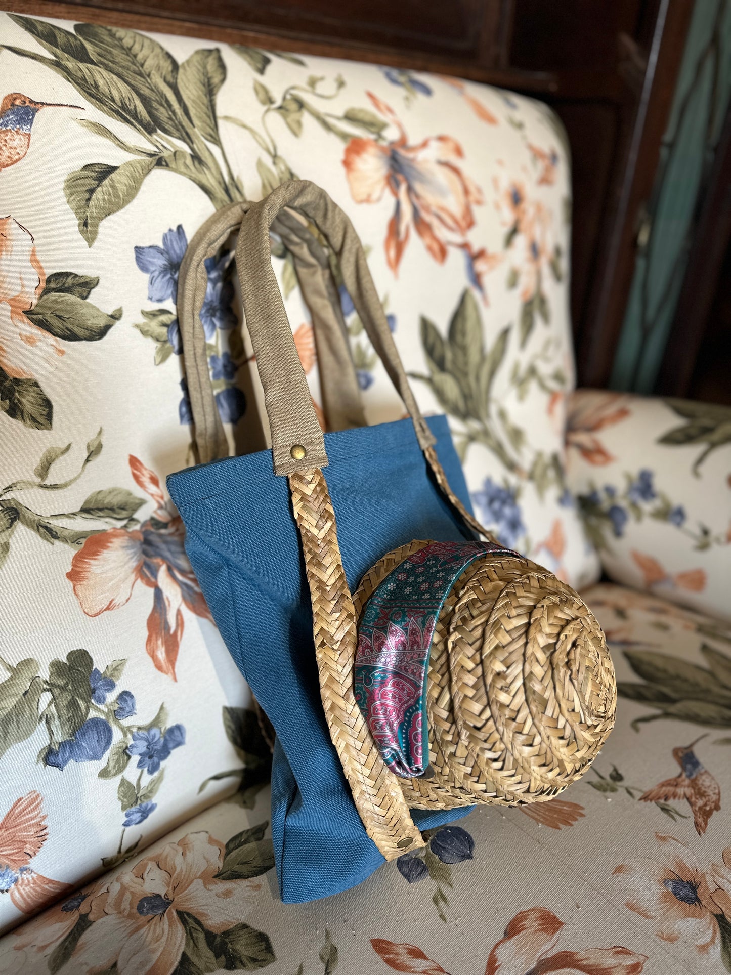 Blue tote bag with straw handles for carrying a hat
